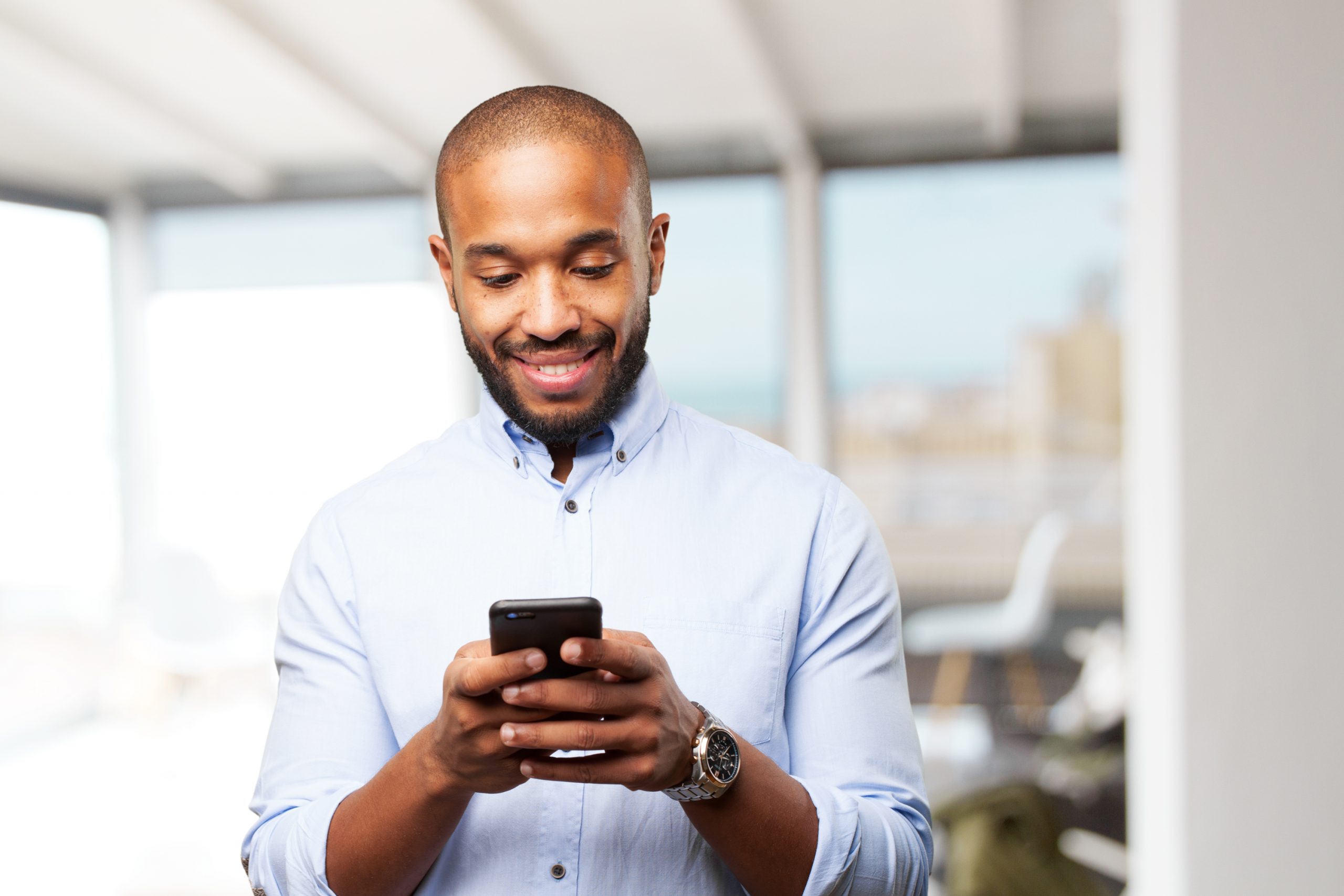 Businessman smiling while on his cellphone that just received a payment request from his practitioner.