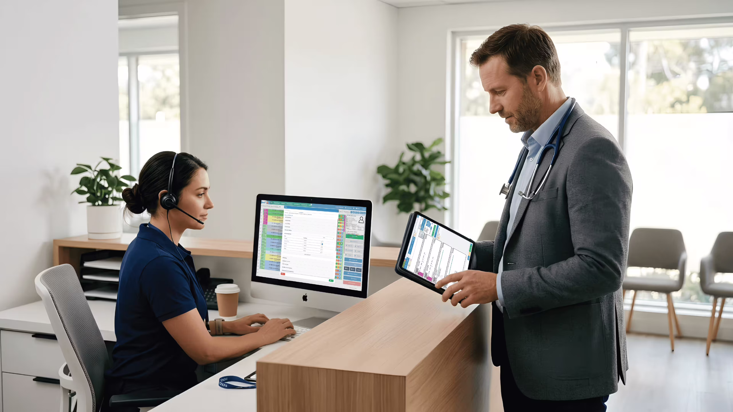 A modern, clean medical office setup with a doctor using a tablet and a receptionist at a computer Doctor and receptionist using practice management software in a modern clinic